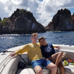 a man sitting on a rock next to a body of water