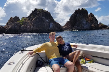 a man sitting on a rock next to a body of water