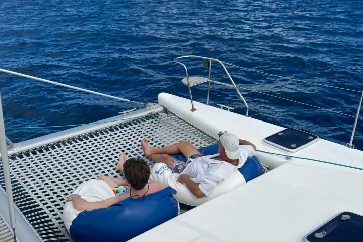 Tw guests relaxing in bean bag chairs on the bow of Seas the Day Charters USVI while sailing on a private catamaran charter, S/Y Leviathan