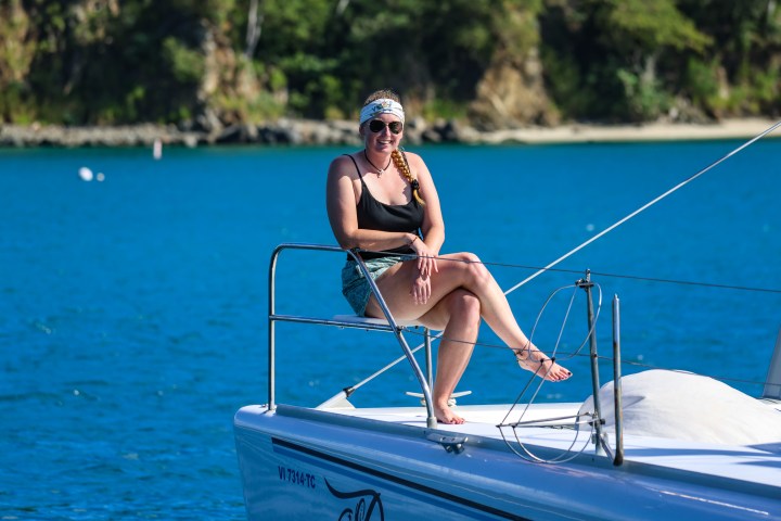 Guest sitting on bow tip of Seas the Day Charters USVI S/Y Pisces