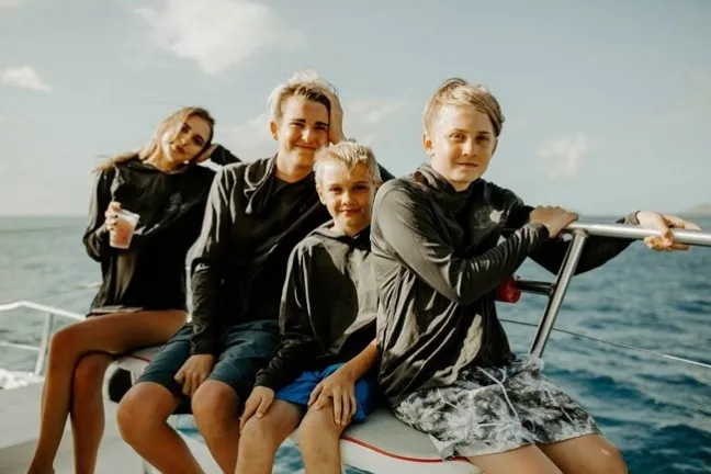 a young boy sitting next to a body of water