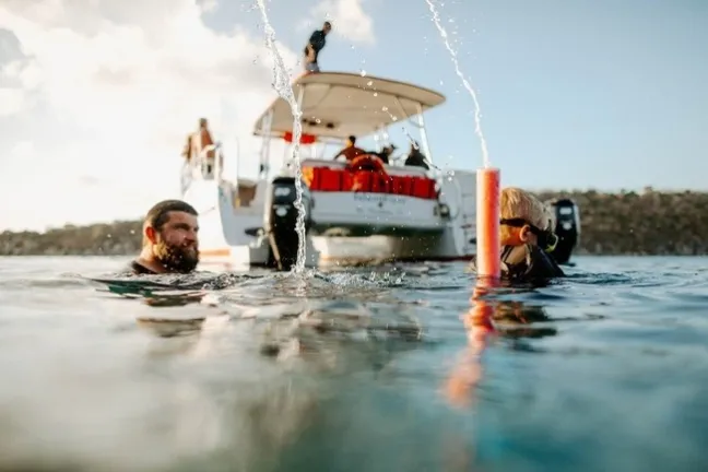 a group of people riding on the back of a boat in the water