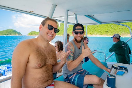 2 Seas the Day Charters USVI guests posing for a photo aboard Party Yacht Sea Wolf while the private charter boat is moored at Maho Bay, St. John