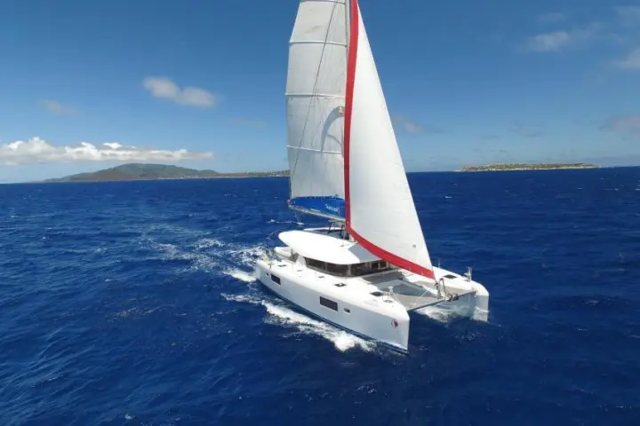 White catamaran sailing in open blue sea under clear sky.