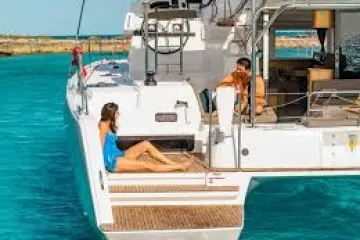 Two people relaxing on a yacht in clear blue water.