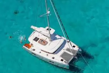 Aerial view of a white catamaran in clear turquoise water with a swimmer nearby.