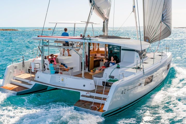People relaxing on a catamaran sailing on clear blue waters.